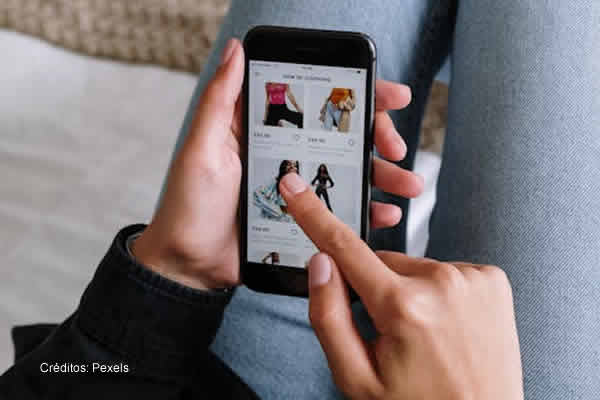 persona recostada en un sillón mirando una tienda en su celular