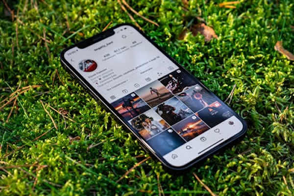 Celular sobre el pasto, con Instagram abierto. Publicaciones para redes sociales